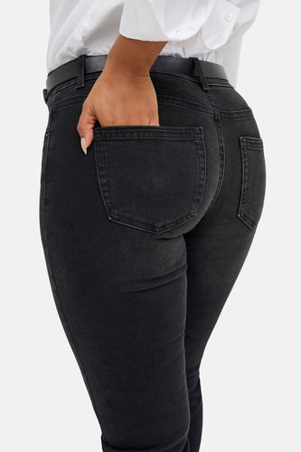 Zwarte flared jeans van ONLY, met een hand in de achterzak en een witte blouse