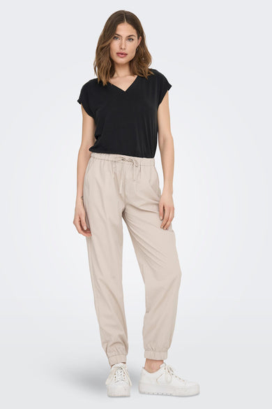 Zwart T-shirt met korte mouwen van ONLY, met V-hals en gedragen met beige broek en witte sneakers.