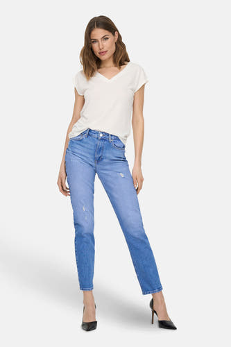 Wit T-shirt van ONLY, gedragen met jeans en zwarte hakken tegen een witte achtergrond.

