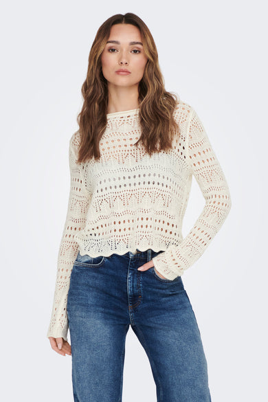 Pull-over blanc à col rond de JDY, en tissu tricoté ouvert, porté sur un haut et un short de denim foncé.