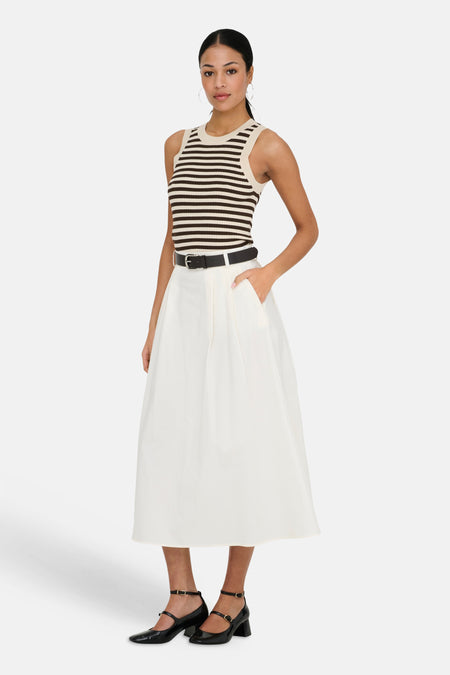 Mouwenloze gestreepte top in beige en donkerbruin van JDY, gecombineerd met een witte midi-rok en zwarte Mary Jane schoenen.