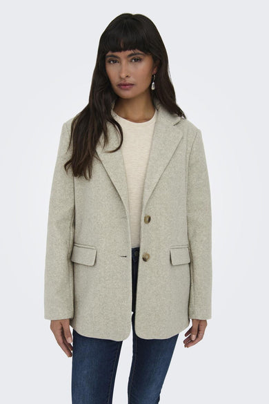 Beige korte jas van ONLY, met knoopsluiting en opgestikte zakken, gedragen met een crème shirt en donkere jeans.
