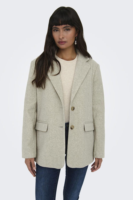 Beige korte jas van ONLY, met knoopsluiting en opgestikte zakken, gedragen met een crème shirt en donkere jeans.
