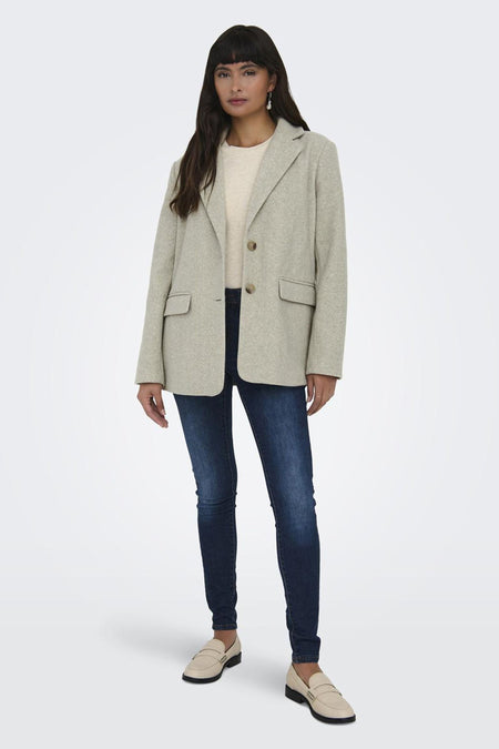 Beige korte jas van ONLY, met lange mouwen, gedragen met donkere jeans en beige loafers.
