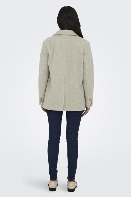Beige korte jas van ONLY, met knoopsluiting, gedragen met een donkere jeans en crèmekleurige schoenen.