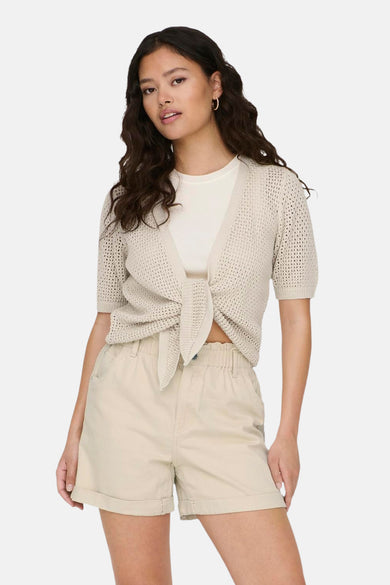 Beige vest van JDY met korte mouwen en knoopdetail, gedragen over een wit T-shirt en met beige shorts.
