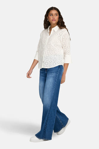 Wit hemd met lange mouwen van JDY, met broderie details en gedragen met een donkerblauwe jeans en witte sneakers.