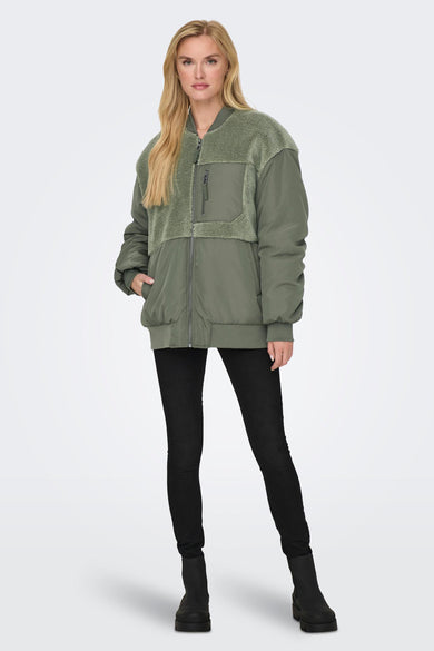 Groene jas van ONLY, met teddy details en gecombineerd met zwarte jeans en enkellaarsjes.
