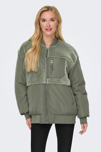 Groene jas van ONLY met teddy detail op de schouders en zwarte broek.
