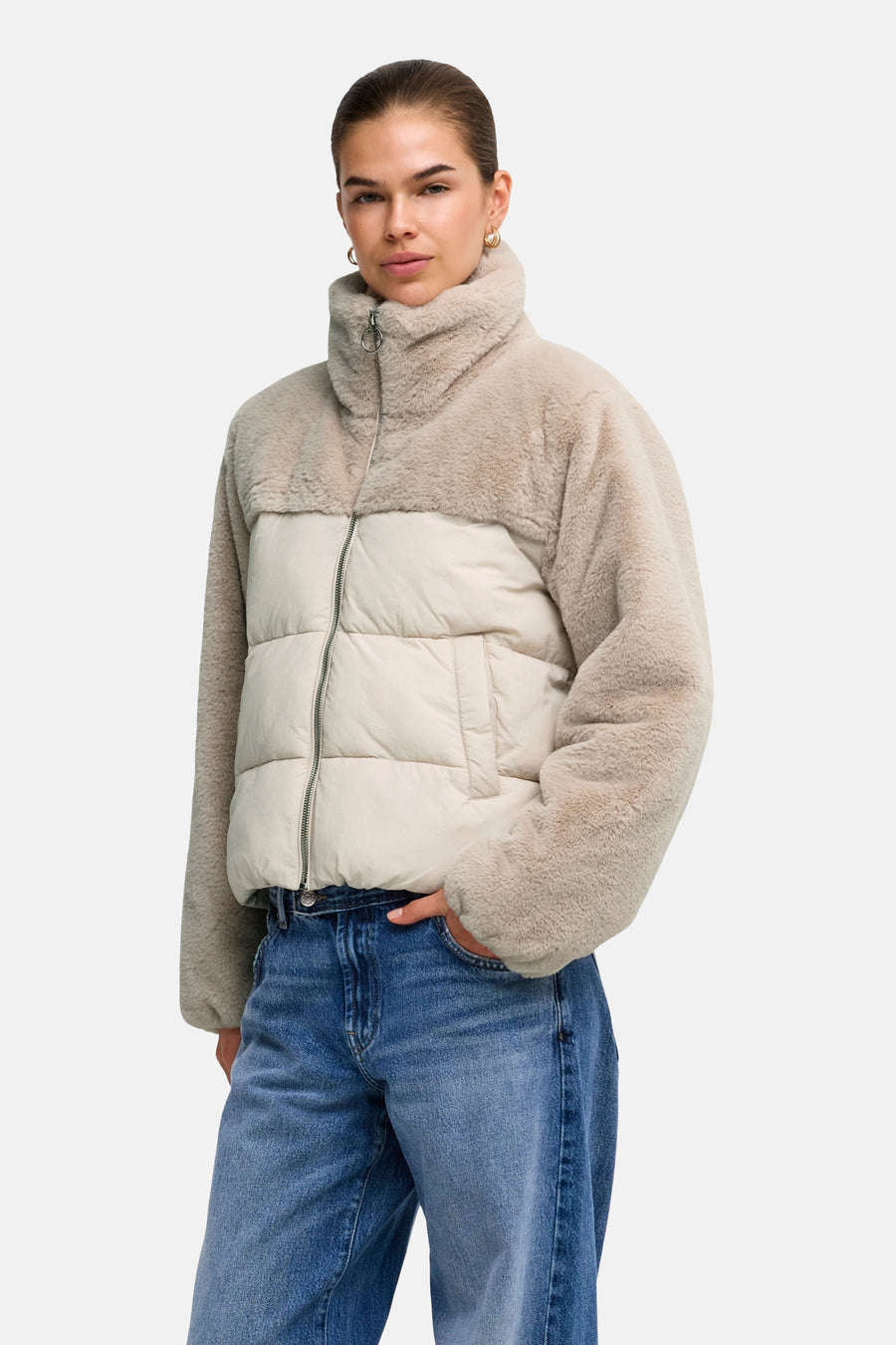 Lichtgrijze pufferjas met teddybontmouwen en kraag van ONLY®, voorzien van rits en zakken, gedragen met blauwe jeans.