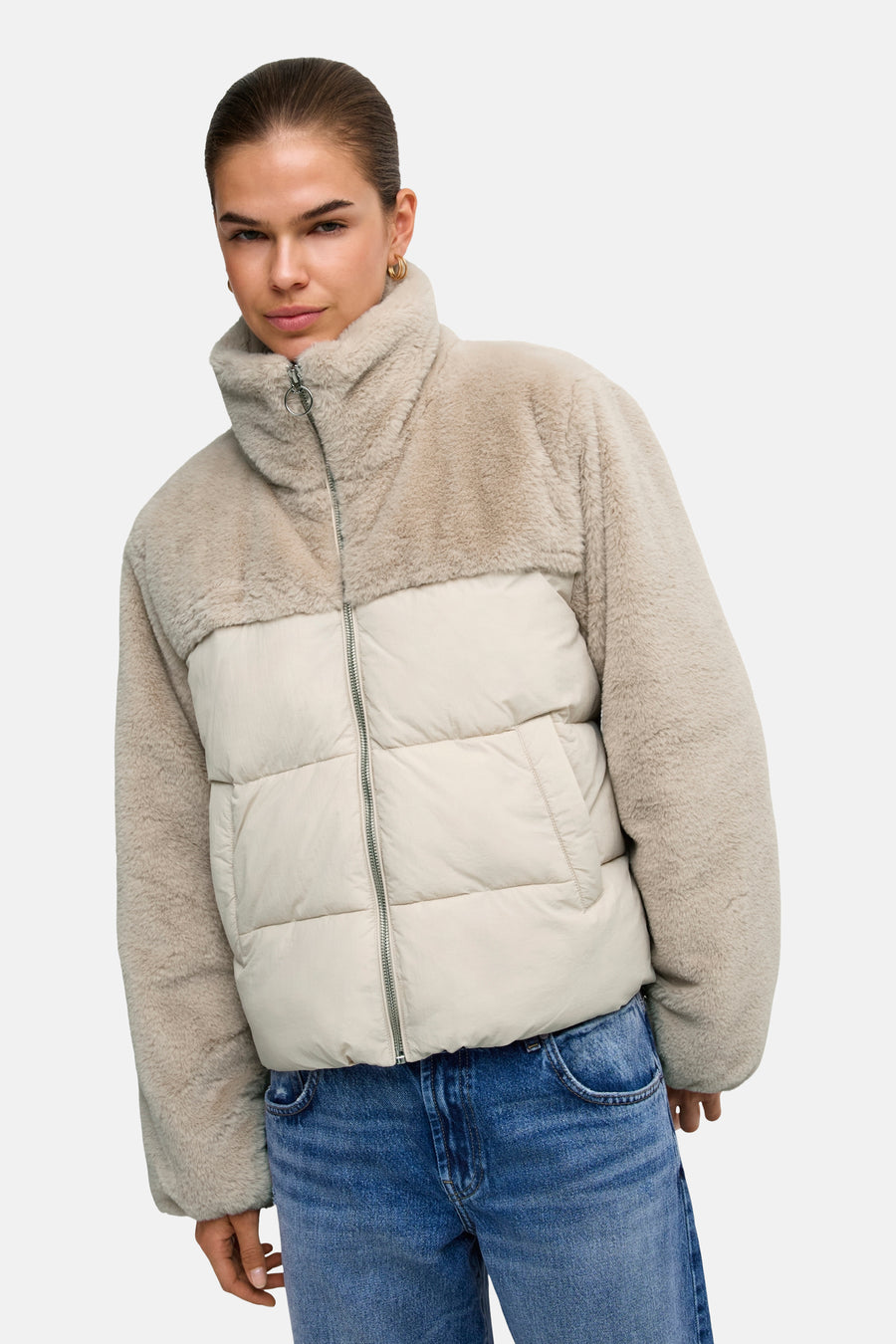 Lichtgrijze pufferjas met bontlook capuchon en crèmekleurig gestoffeerd middenstuk van ONLY®, vooraanzicht, model draagt blauwe jeans