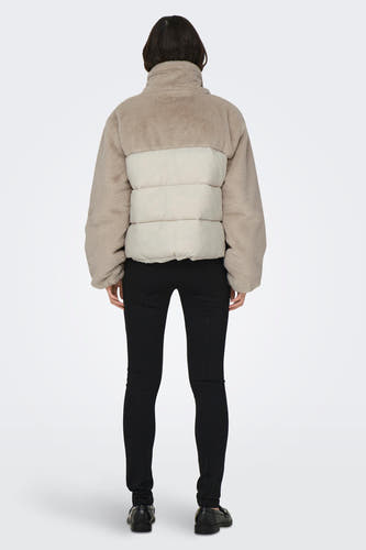 Ecru korte jas van ONLY, met fleece textuur en gewatteerde panelen op de rug, gecombineerd met zwarte broek en schoenen.
