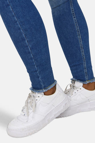 Jean skinny bleu marine en denim d'ONLY, avec un bord côtelé et des baskets blanches.