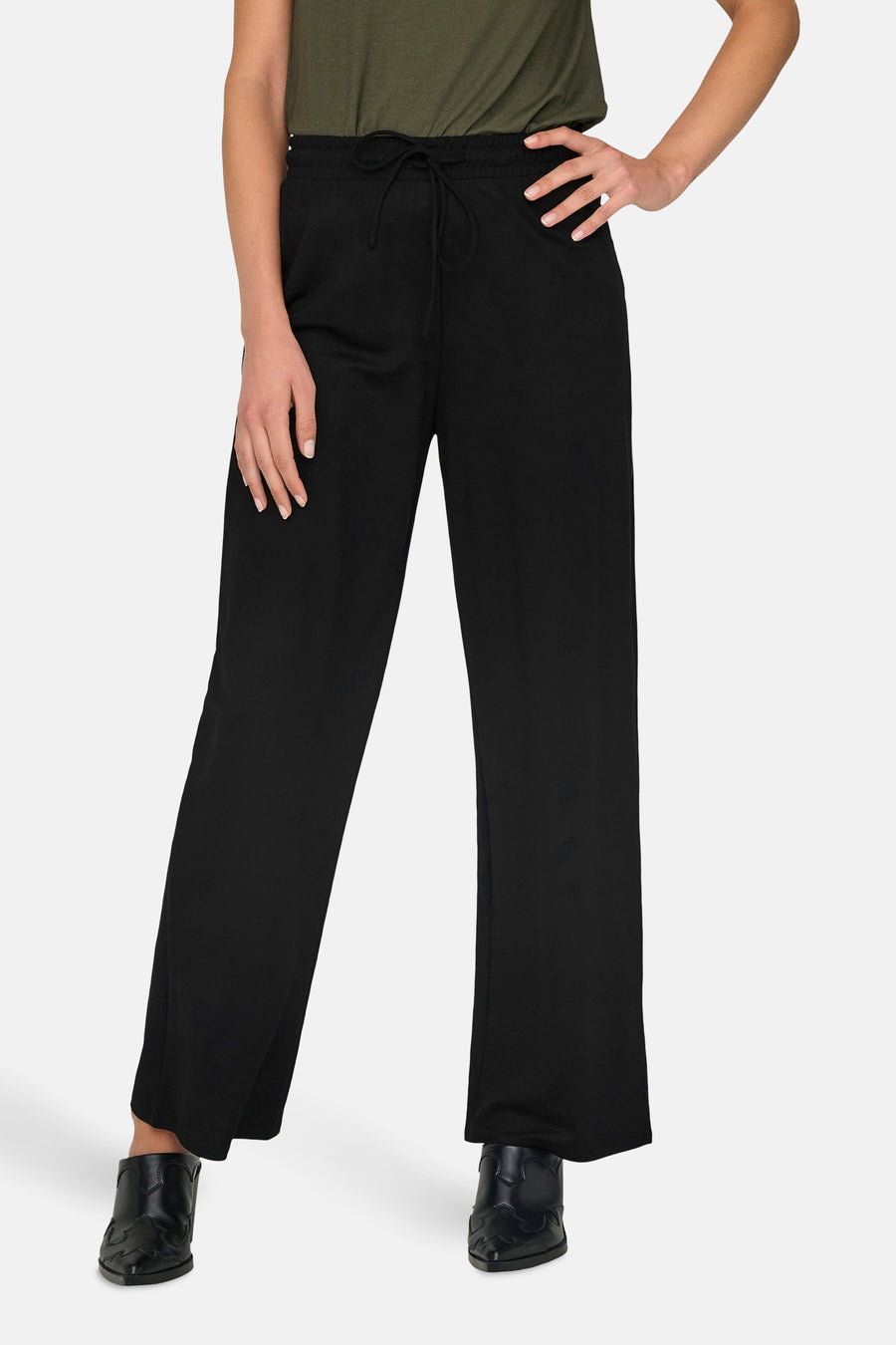 Zwarte broek van ONLY, met trekkoord, gedragen met een groen shirt en zwarte schoenen.
