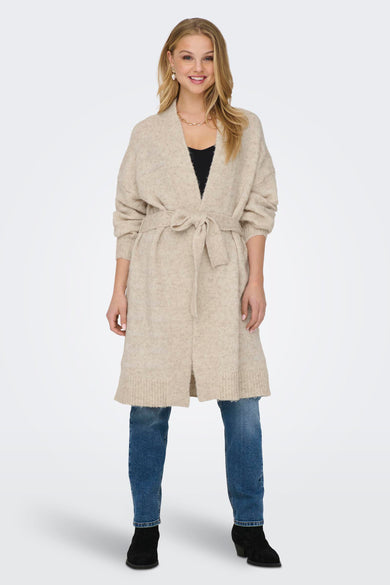 Beige gilet van ONLY, met strikceintuur, gedragen over een zwarte top en blauwe jeans.
