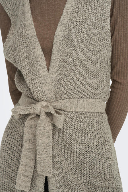 Bruin gilet van JDY, gebreid met een ceintuur in de taille en gedragen over een bruine top.
