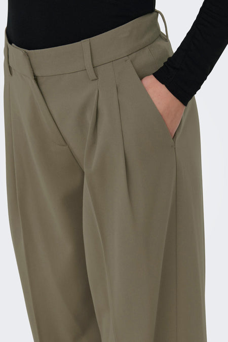 Grijze broek van ONLY, met plooien en een hand in de zak.

