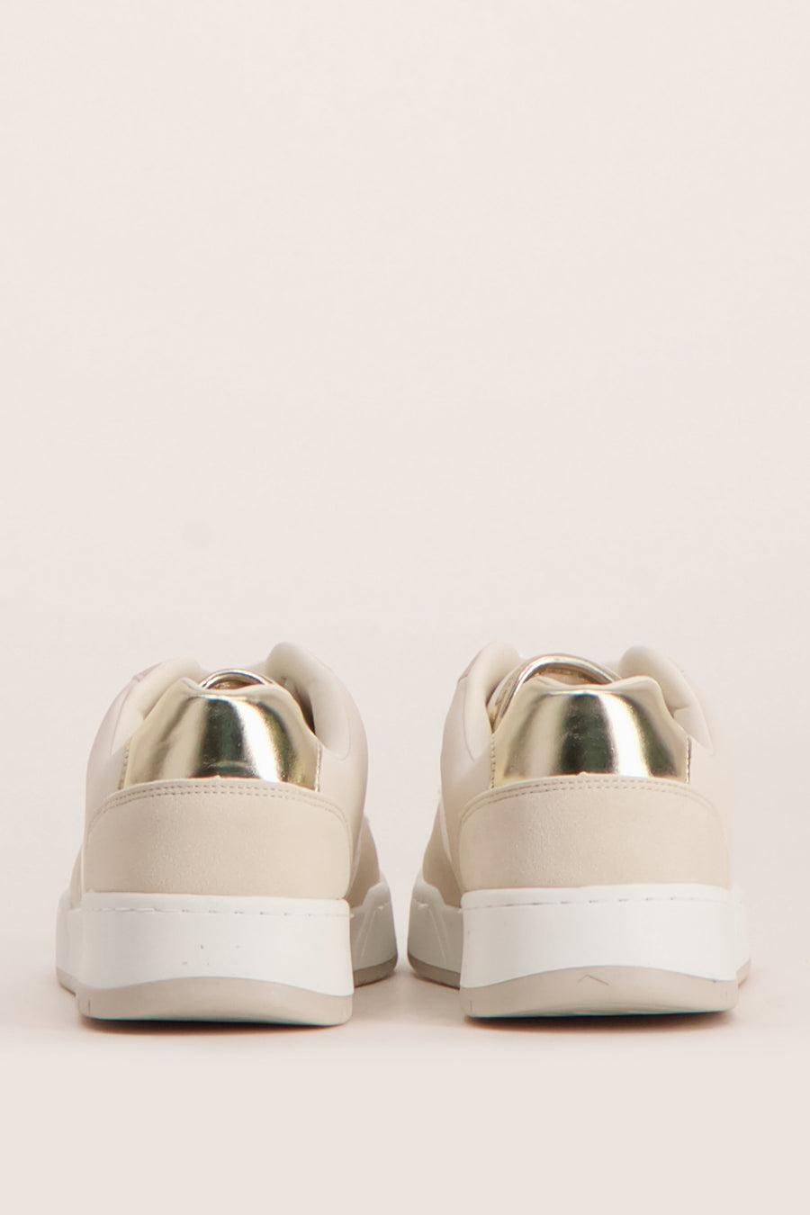 Crèmekleurige sneakers met gouden accenten.