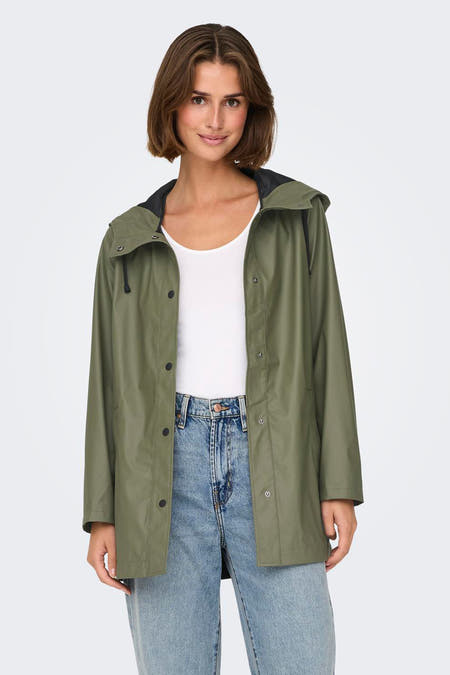 Groene regenjas van ONLY, met een kap, knoopsluiting en gecombineerd met een witte top en blauwe jeans.
