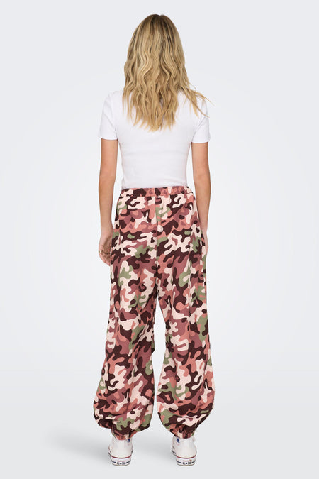 Camo broek van NEON & NYLON, losse pasvorm, met een witte top en Converse All Stars sneakers.
