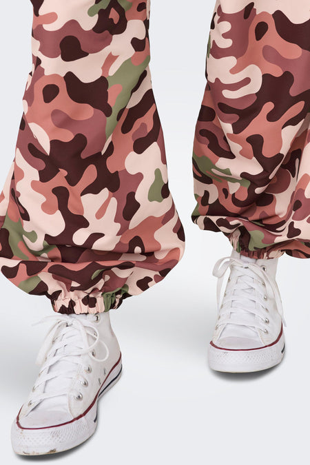 Roze camouflage broek van NEON & NYLON, gecombineerd met witte sneakers met veters.