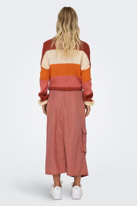 Roze rok van NEON & NYLON, driekwart lengte, met cargozakken en gedragen met een gestreepte trui.