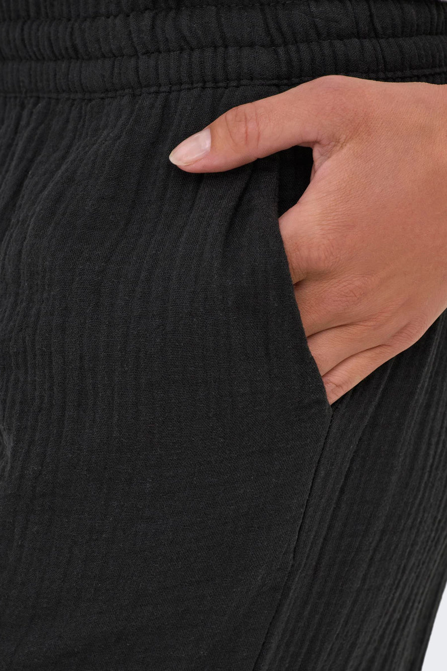 Pantalon noir de JDY, avec un détail texturé et une main dans la poche.
