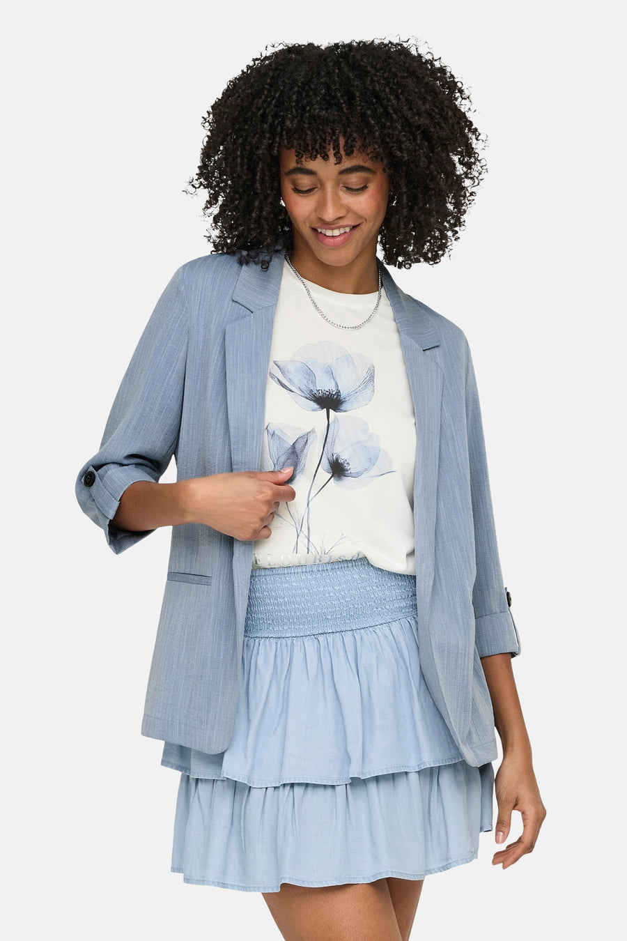 Blazer bleue de ONLY, avec manches trois-quarts et détails de boutons, combinée avec un haut blanc et une jupe bleu clair.
