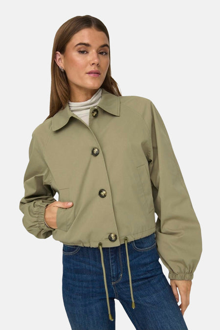Manteau court vert de ONLY, avec des manches longues, une fermeture à boutons et un jeans bleu.