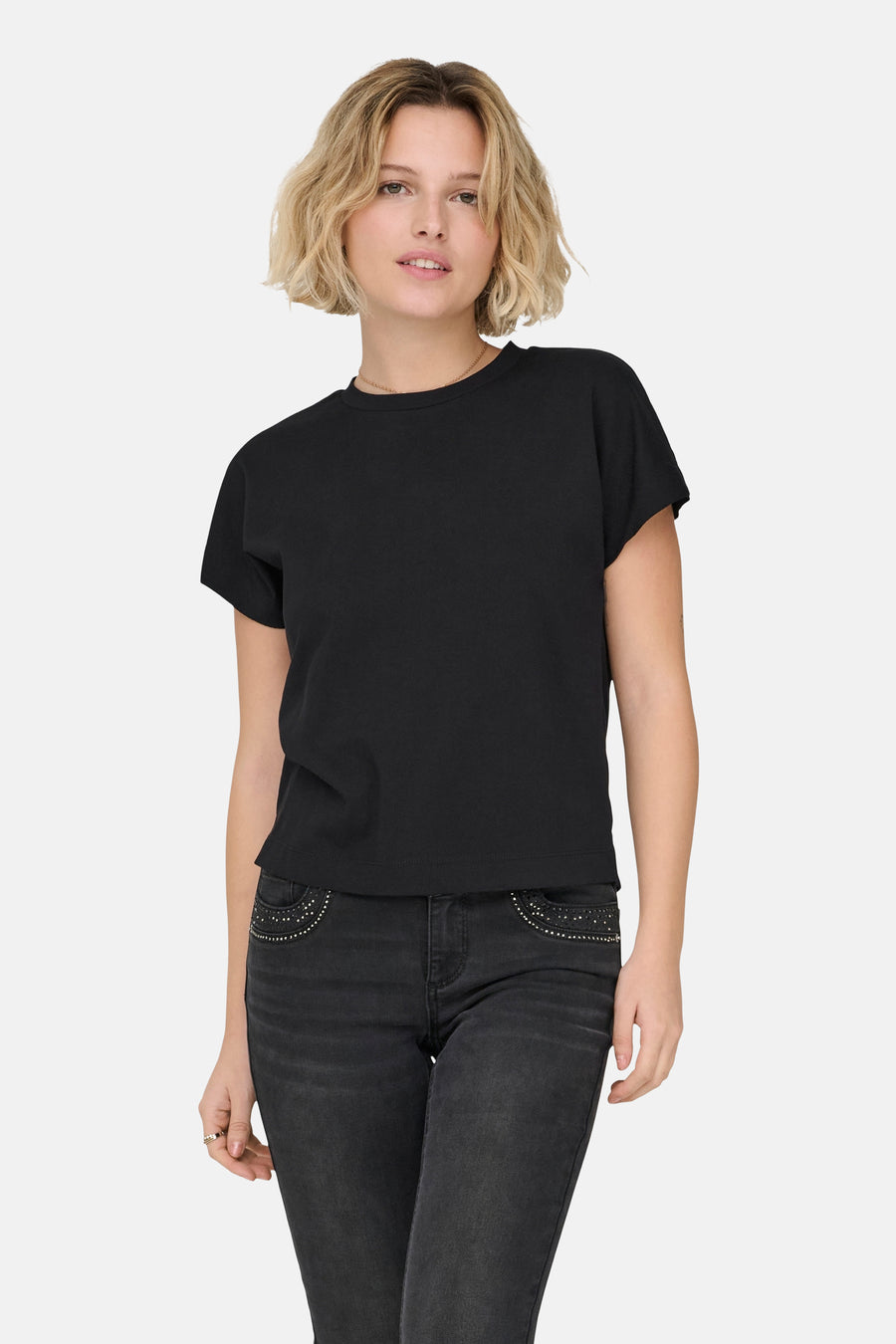 T-shirt noir à manches courtes de ONLY, porté avec un jean foncé orné de surpiqûres sur les poches.