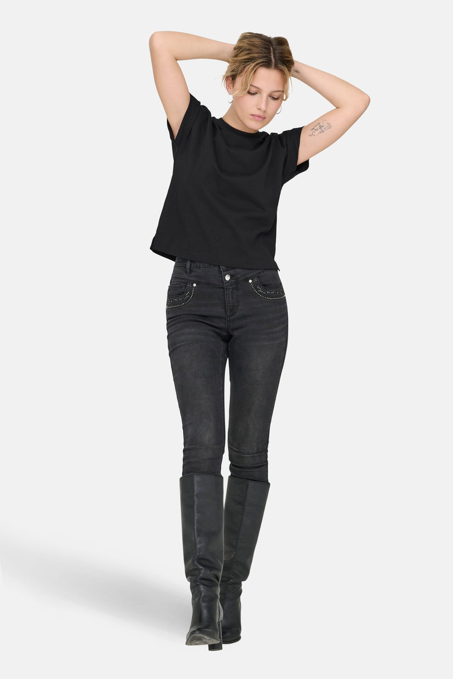 T-shirt noir à manches courtes de ONLY, porté avec un jean foncé et des bottes noires.