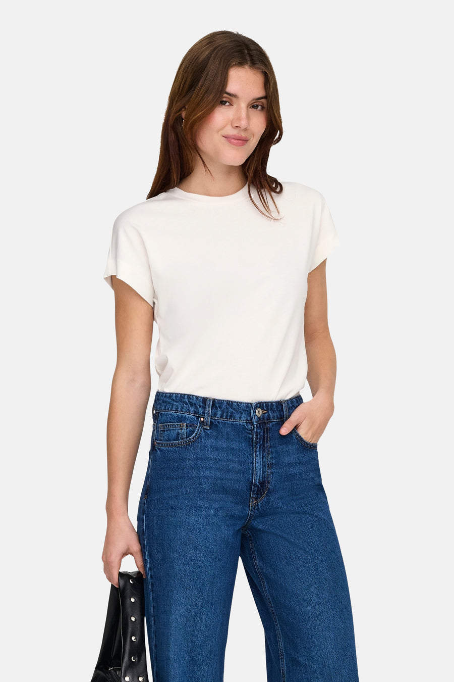 T-shirt blanc à manches courtes ONLY®, porté avec un jean ample et un sac à main noir.