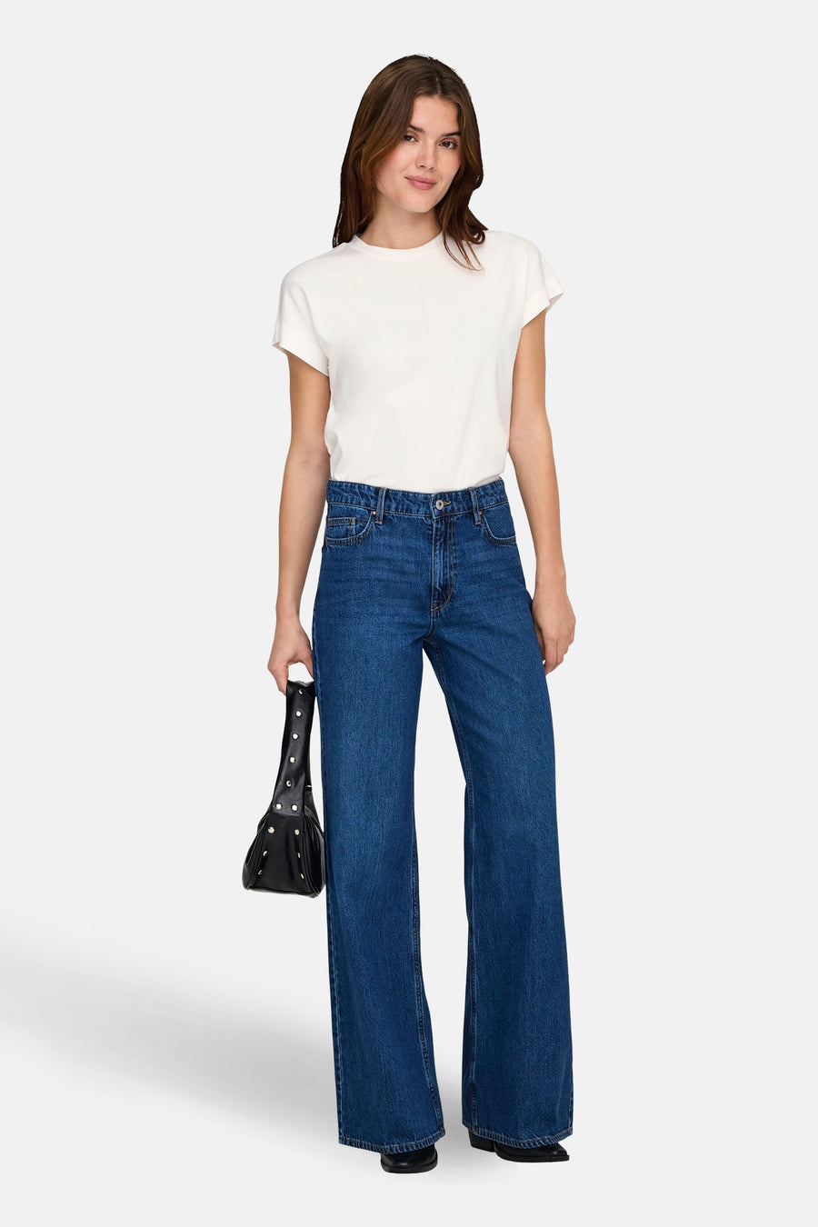 Wit T-shirt met korte mouwen van ONLY®, gedragen met wijde jeans en een zwarte handtas.