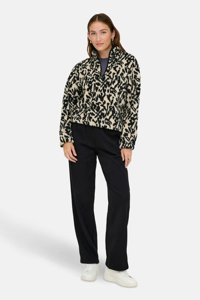 Zwarte fleece van ONLY, met een zwart en beige dierenprint, gedragen met een zwarte broek en witte sneakers.
