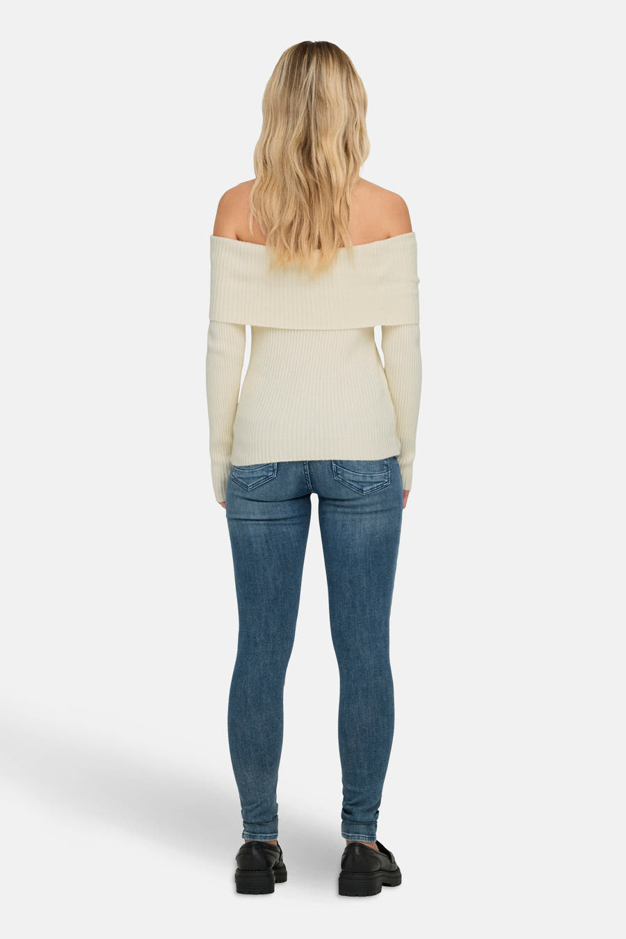 Witte offshoulder trui van ONLY, gezien van achteren, gecombineerd met blauwe jeans en zwarte schoenen.

