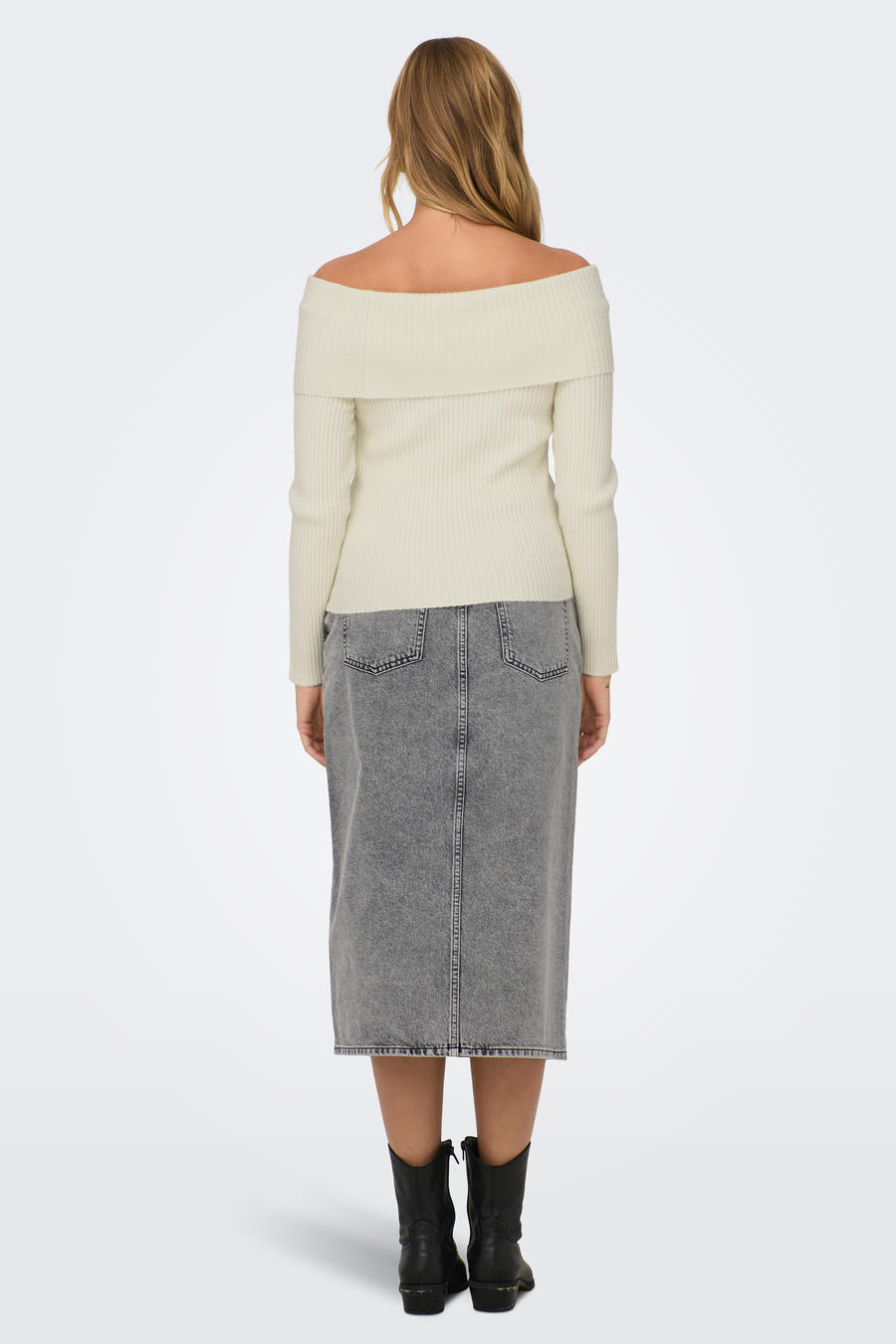 Witte offshoulder trui van ONLY, met lange mouwen en een ribgebreide textuur, gedragen met een grijze rok en zwarte laarzen.
