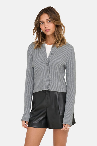Grijs vest van ONLY, met knoopsluiting, gedragen over een wit shirt en gecombineerd met zwarte leren shorts.
