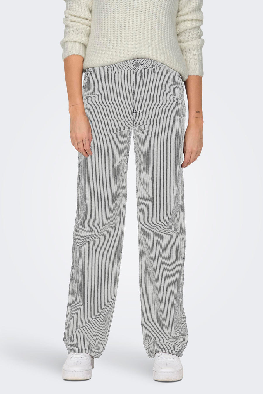 Witte broek van ONLY®, met een fijn gestreept patroon, gecombineerd met een gebreide trui en witte sneakers.
