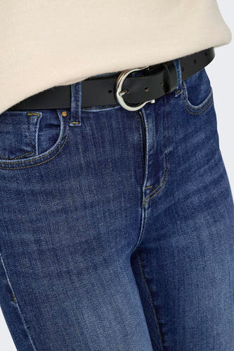 Close-up van donkerblauwe skinny jeans van het merk ONLY, met gele stiksels, een zwarte riem en zilveren gesp.