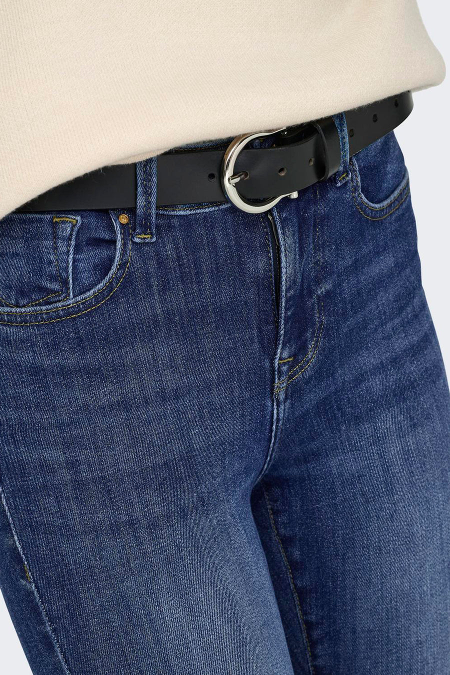 Close-up van donkerblauwe skinny jeans van het merk ONLY, met gele stiksels, een zwarte riem en zilveren gesp.