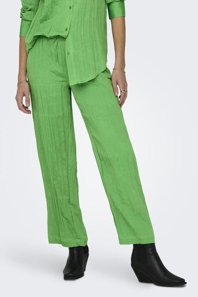 Groene broek van ONLY met een gekreukte textuur, gecombineerd met zwarte laarzen en gouden sieraden.
