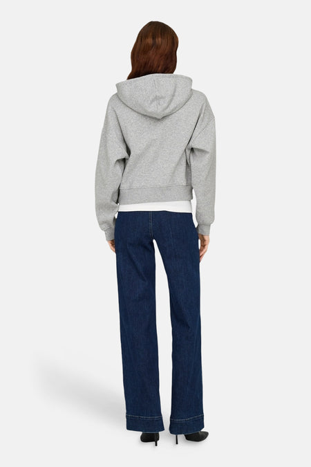 Grijze sweater met kap van ONLY, met lange mouwen, gecombineerd met donkerblauwe jeans en zwarte hakken, rugaanzicht.

