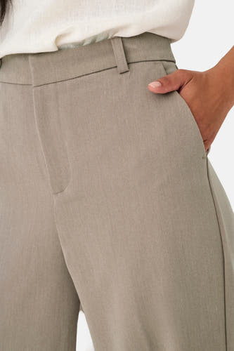 Pantalon de costume beige ONLY, avec poches et une main dans la poche.