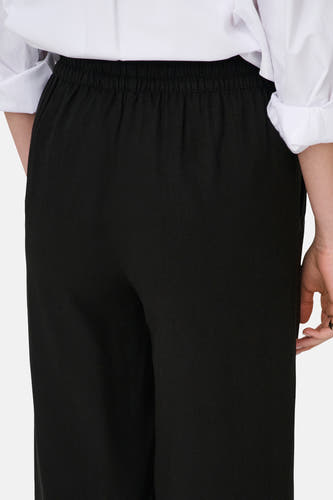Pantalon noir de JDY, avec une taille élastique, porté avec une chemise blanche.