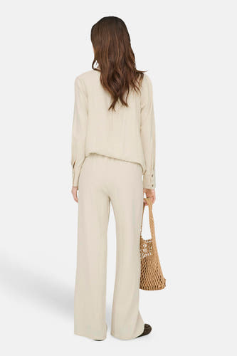 Beige broek van JDY in wijd model, gedragen met bijpassend overhemd en nettas, rugaanzicht.