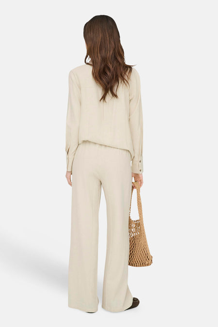 Pantalon beige de JDY coupe ample, porté avec une chemise assortie et un sac en filet, vue de dos.