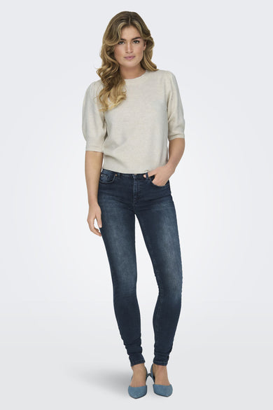 Witte trui met ronde hals van ONLY, gecombineerd met donkere jeans en blauwe pumps.