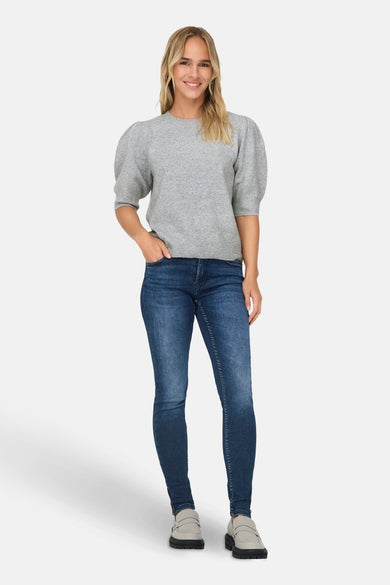 Grijze trui met ronde hals van ONLY, met pofmouwen, gecombineerd met donkere jeans en grijze loafers.
