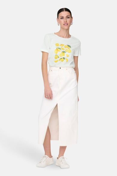 T-shirt blanc à manches courtes de JDY, avec imprimé citron, associé à une jupe blanche et des baskets blanches.