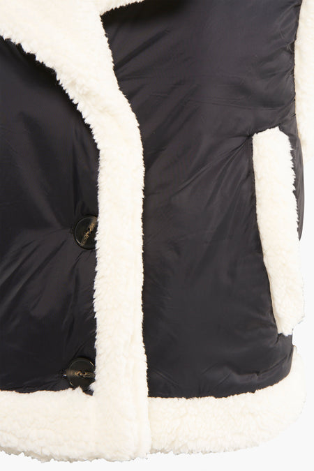 Doudoune sans manches noire de NEON & NYLON avec finition en fausse fourrure blanche et boutons, gros plan sur le devant